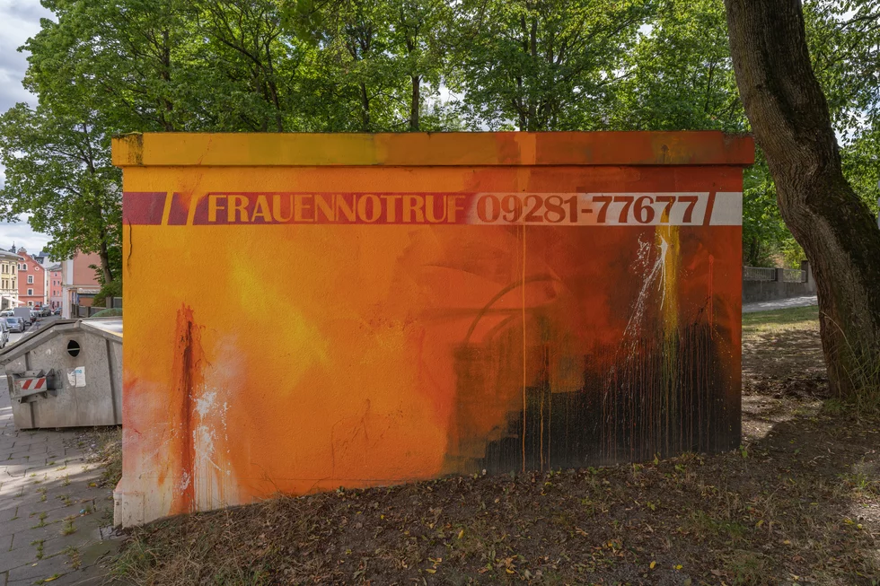 Ansicht eines Stromhäuschens mit einem Wandbild des Frauennotrufs. Hiermit will man für den Notruf werben, damit Frauen, die beispielsweise häuslicher Gewalt ausgesetzt sind, motiviert werden, sich zu melden.